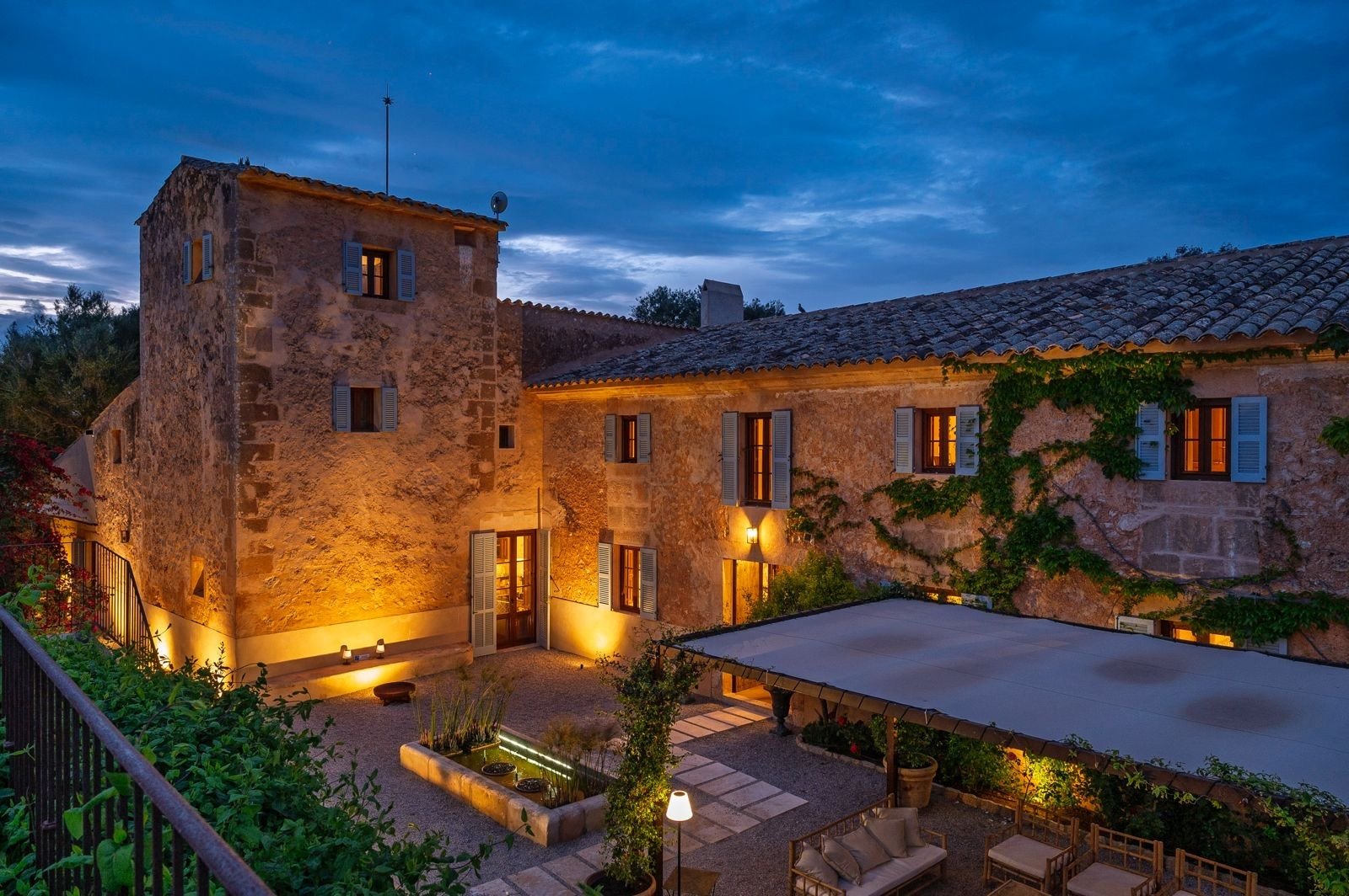 The villa’s blue-shuttered tower and courtyard illuminated after dark
