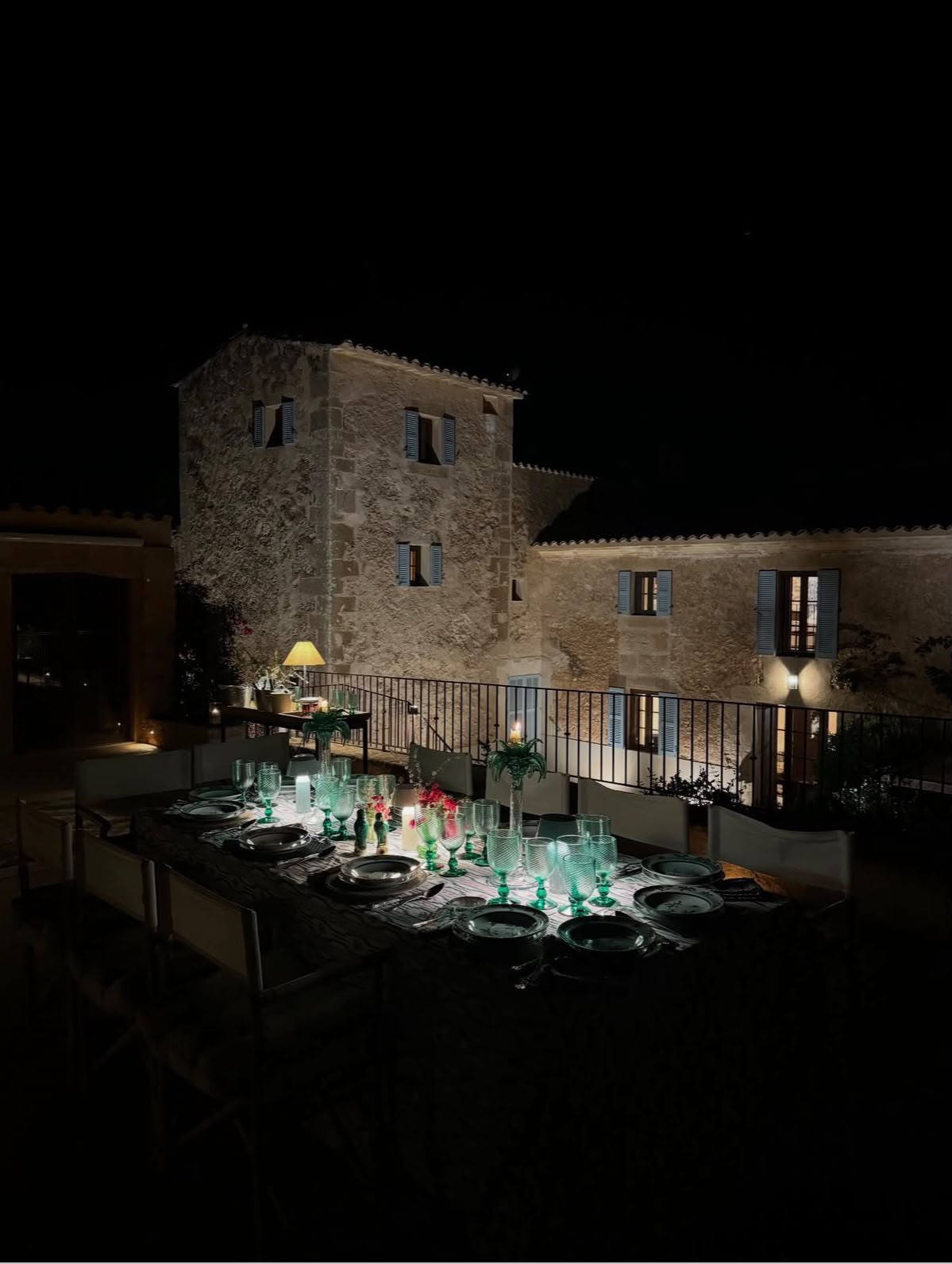 The villa’s stone facade and candlelit terrace after dark